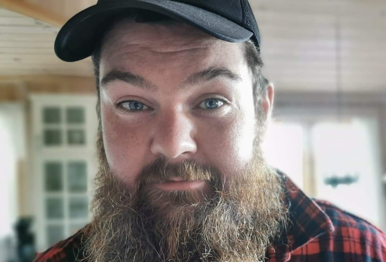 Christoffer Lian. Ung mann med heilskjegg, caps og ruteskjorte.